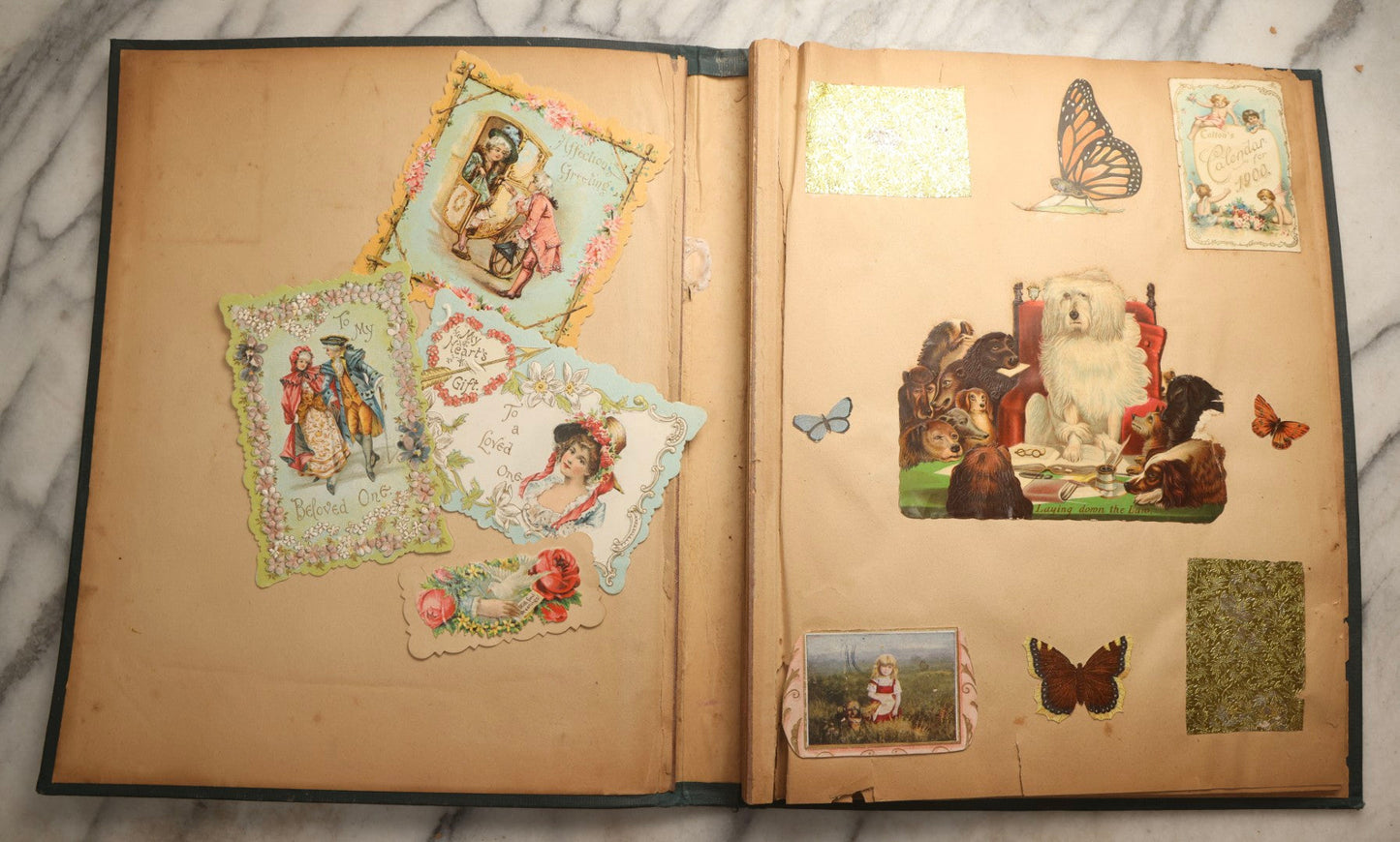 Lot 096 - Antique "The Nonpareil" Scrapbook, Puppies Illustration On Cover, With 100+ Trade Cards, Die Cuts, And Greeting Cards Featuring Children, Butterflies, And Flowers, Circa 1900-1906, Note Binding Detached