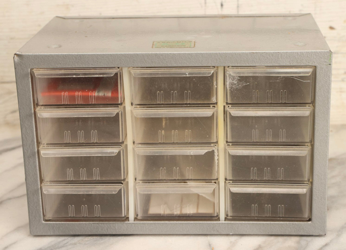 Lot 123 - Vintage A-M Cabinets Silver Metal 21-Drawer Parts Organizer With Original Paper Advertising And Labeling Supplies, Manufactured By Akro-Mils, Akron, Ohio