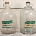 Lot 087 - Pair Of Vintage Clear Glass Jugs With Later-Applied Green “Formaldehyde” Paper Labels From Florida Hardware Co., 11-1/2" H Each