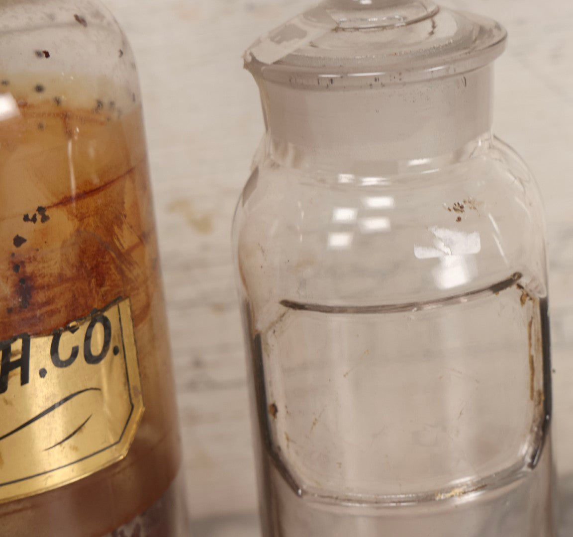 Lot 090 - Trio Of Antique Apothecary Glass Bottles With Ground Stoppers, Mixed Sizes, Worn And Partially Detached Labels, Residue And Staining, Poor As-Found Condition