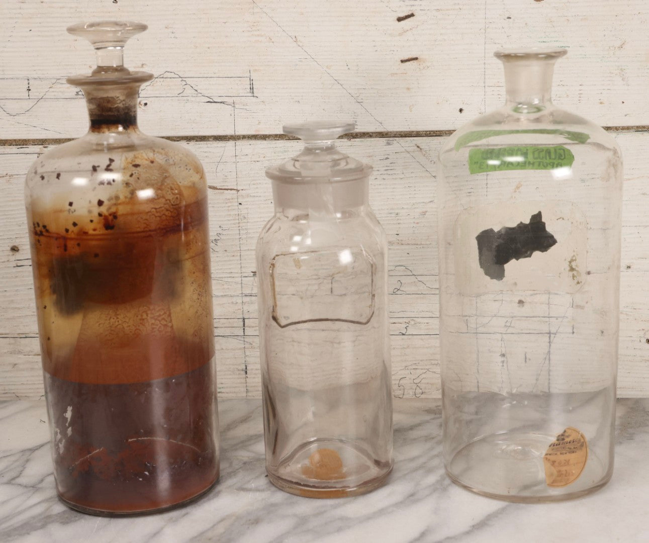 Lot 090 - Trio Of Antique Apothecary Glass Bottles With Ground Stoppers, Mixed Sizes, Worn And Partially Detached Labels, Residue And Staining, Poor As-Found Condition