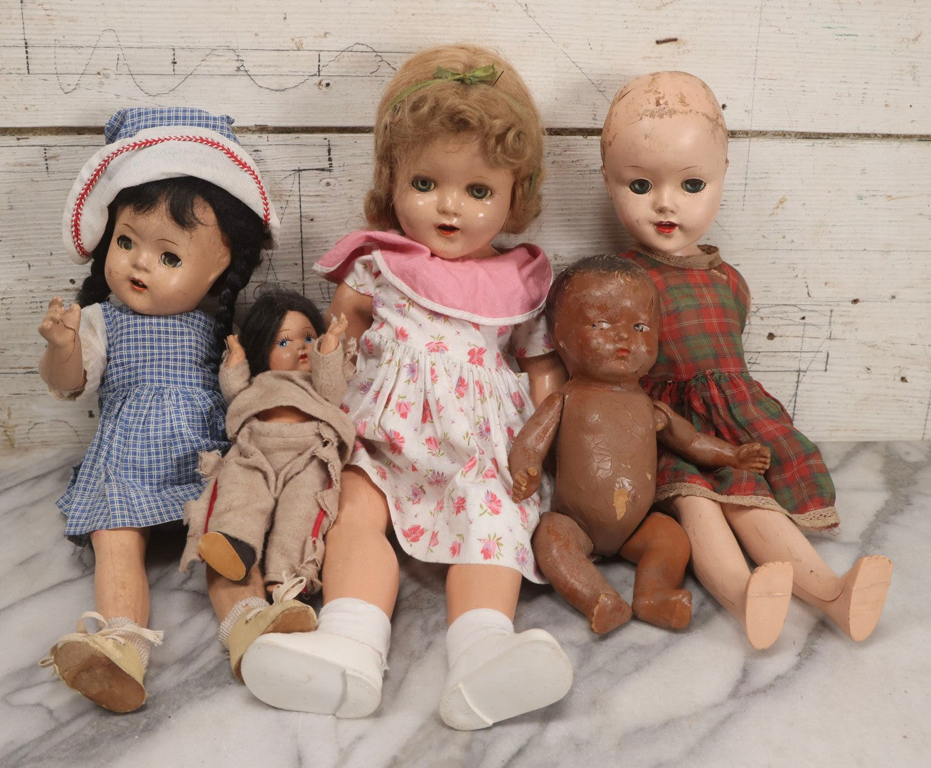 Lot 096 - Grouping Of Five Vintage Composition Dolls Including Floral Dress Doll, Plaid Dress Doll, Blue Check Dress Doll With Bonnet, Brown Composition Baby, And Small Jointed Doll
