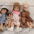 Lot 096 - Grouping Of Five Vintage Composition Dolls Including Floral Dress Doll, Plaid Dress Doll, Blue Check Dress Doll With Bonnet, Brown Composition Baby, And Small Jointed Doll