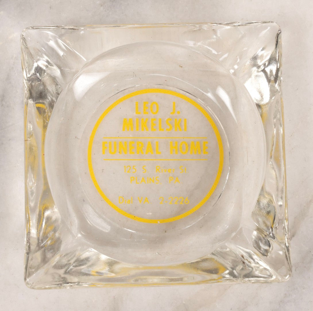 Lot 119 - Vintage Clear Glass Funeral Home Advertising Ashtray With Yellow Lettering For Leo J. Mikelski Funeral Home, Plains, Pennsylvania