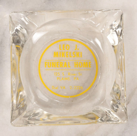 Lot 119 - Vintage Clear Glass Funeral Home Advertising Ashtray With Yellow Lettering For Leo J. Mikelski Funeral Home, Plains, Pennsylvania