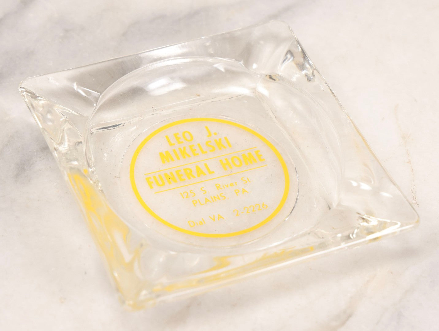 Lot 119 - Vintage Clear Glass Funeral Home Advertising Ashtray With Yellow Lettering For Leo J. Mikelski Funeral Home, Plains, Pennsylvania