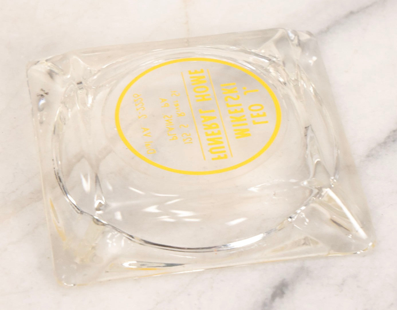 Lot 119 - Vintage Clear Glass Funeral Home Advertising Ashtray With Yellow Lettering For Leo J. Mikelski Funeral Home, Plains, Pennsylvania