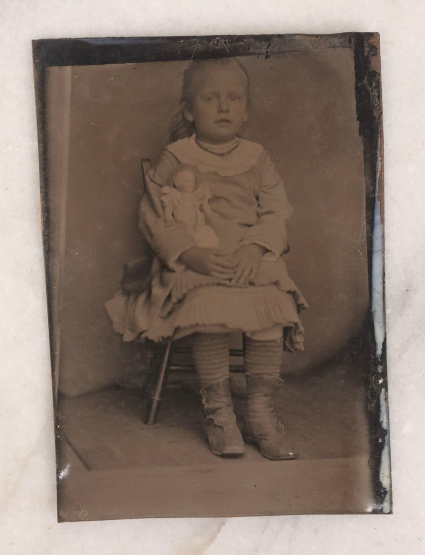 Lot 141 - Single Antique Tintype Photograph Of A Young Girl Seated In A Small Wooden Chair With Her Doll Tucked Under Her Arm