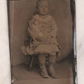Lot 141 - Single Antique Tintype Photograph Of A Young Girl Seated In A Small Wooden Chair With Her Doll Tucked Under Her Arm