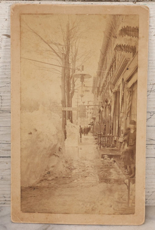 Lot 150 - Antique Boudoir-Sized Cabinet Card Photograph Depicting Street Scene Aftermath Of Great Blizzard Of 1888, New York City, With Snow Banks, Pedestrians, And "Butterick's Patterns" Storefront Visible