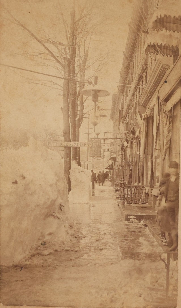 Lot 150 - Antique Boudoir-Sized Cabinet Card Photograph Depicting Street Scene Aftermath Of Great Blizzard Of 1888, New York City, With Snow Banks, Pedestrians, And "Butterick's Patterns" Storefront Visible