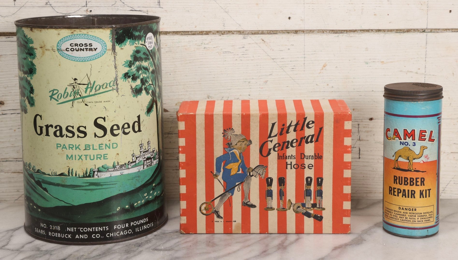 Lot 262 - Trio Of Vintage And Antique Advertising Pieces Including Grass Seed Tin, Camel Tire Tube Repair Kit, And “Little General Infants Durable Hose” Undergarments Box, W.T. Grant Co., 1923