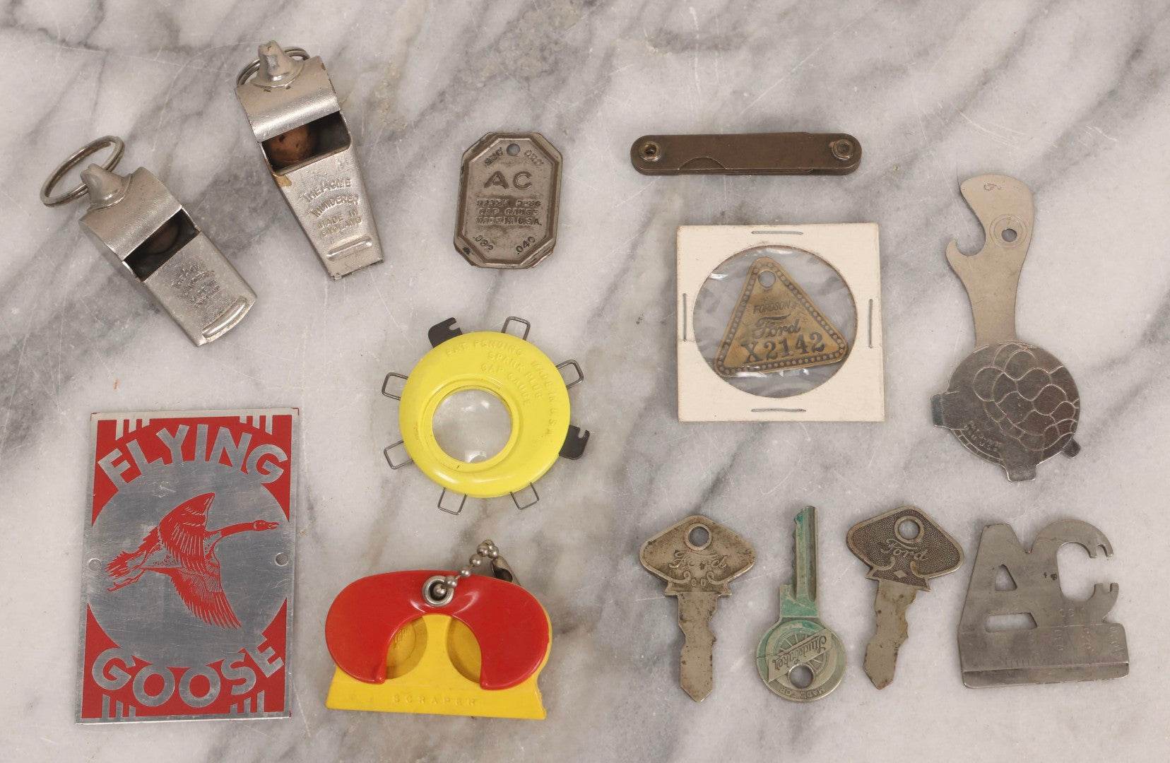 Lot 274 - Grouping Of 13 Vintage Advertising And Metal Pieces Including Ford And Studebaker Keys, Sutter's Hi Speed Turtle Bottle Opener, Acme Thunderer Whistles, S.S. Kresge Co. Feeler Gauge, And Shell Service Scraper