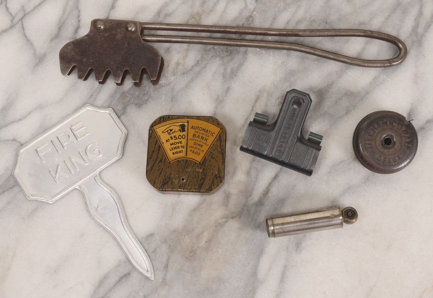 Lot 275 - Grouping Of Six Vintage Metal Objects Including Fire King Aluminum Rose Garden Marker, Cast Iron Meat Tenderizer, Schrader Tire Pressure Gauge, Lucky Dime Register Bank, Esterbrook Clip, And Mechanics Pal Tape Measure