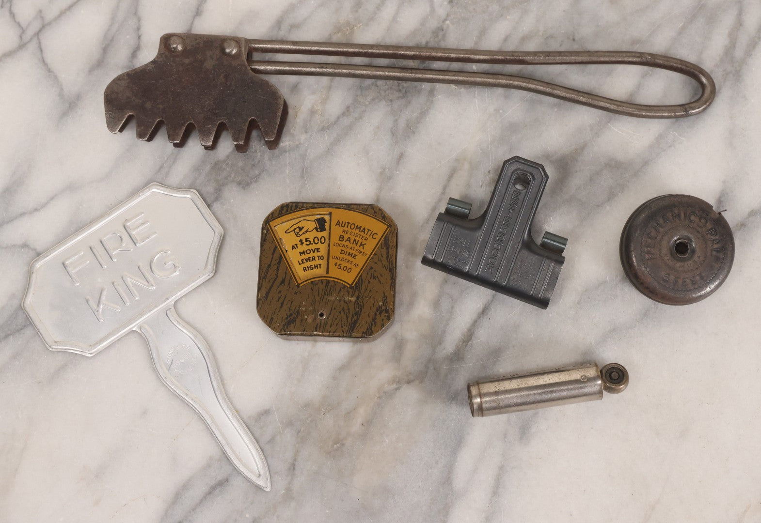 Lot 275 - Grouping Of Six Vintage Metal Objects Including Fire King Aluminum Rose Garden Marker, Cast Iron Meat Tenderizer, Schrader Tire Pressure Gauge, Lucky Dime Register Bank, Esterbrook Clip, And Mechanics Pal Tape Measure