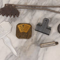 Lot 275 - Grouping Of Six Vintage Metal Objects Including Fire King Aluminum Rose Garden Marker, Cast Iron Meat Tenderizer, Schrader Tire Pressure Gauge, Lucky Dime Register Bank, Esterbrook Clip, And Mechanics Pal Tape Measure