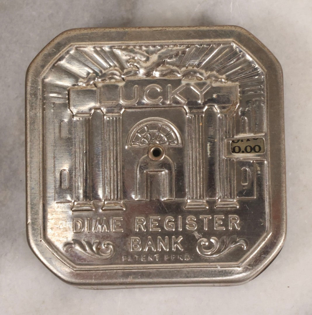 Lot 275 - Grouping Of Six Vintage Metal Objects Including Fire King Aluminum Rose Garden Marker, Cast Iron Meat Tenderizer, Schrader Tire Pressure Gauge, Lucky Dime Register Bank, Esterbrook Clip, And Mechanics Pal Tape Measure