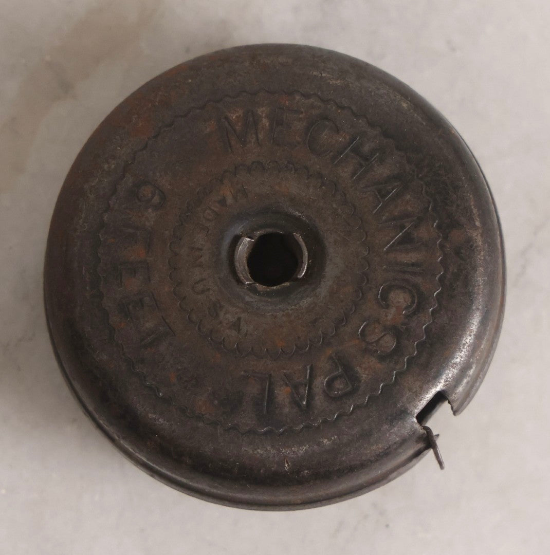 Lot 275 - Grouping Of Six Vintage Metal Objects Including Fire King Aluminum Rose Garden Marker, Cast Iron Meat Tenderizer, Schrader Tire Pressure Gauge, Lucky Dime Register Bank, Esterbrook Clip, And Mechanics Pal Tape Measure