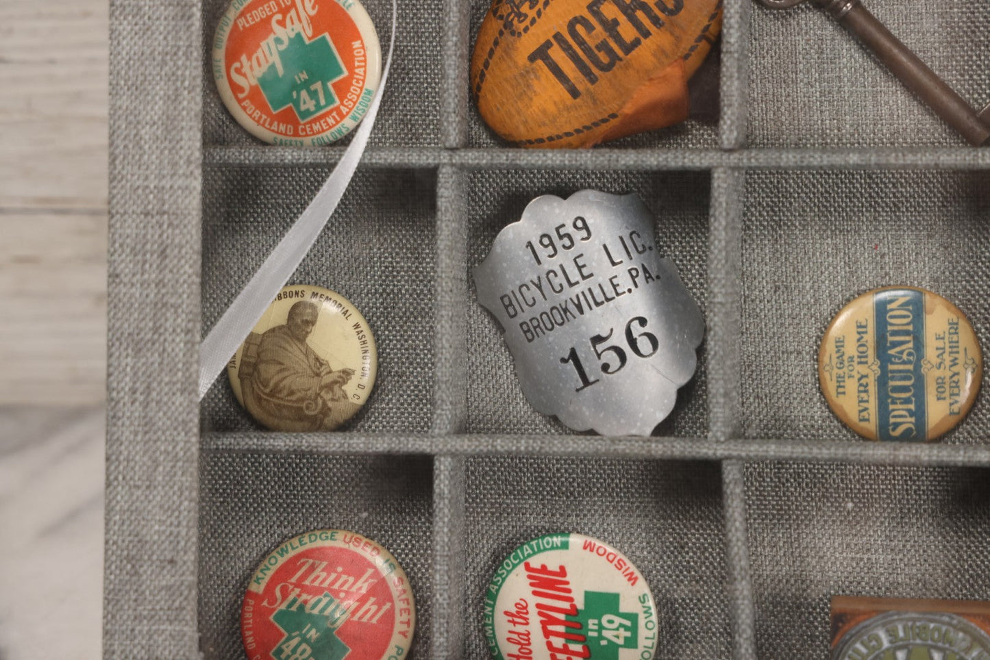 Lot 276 - Modern Display Case With Vintage Smalls And Advertising Pieces Including Candy Machine Door, Bicycle License, Pinback Buttons, Printing Block, And Metal Toy Football Player