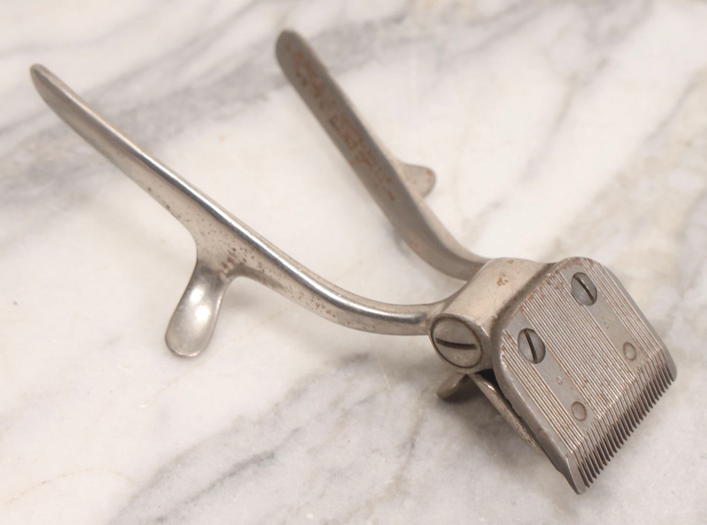 Lot 280 - Grouping Of Four Antique Shaving Items Including Gillette Metal Hot Water Bottle, Hand-Operated Clippers, And Stag Co. Razor Blade Sharpener