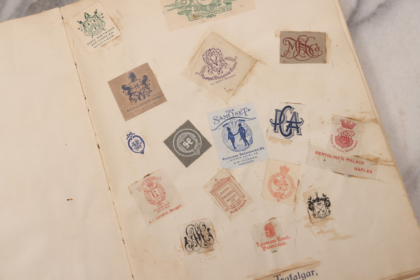 Lot 294 - Antique Scrapbook With Clipped Logos, Seals, And Institutional Names From Colleges, Hotels, Clubs, Banks, Government Offices, And More, Arranged By Color Throughout 20+ Pages, Marbled Cover Boards