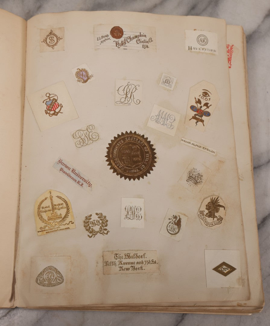 Lot 294 - Antique Scrapbook With Clipped Logos, Seals, And Institutional Names From Colleges, Hotels, Clubs, Banks, Government Offices, And More, Arranged By Color Throughout 20+ Pages, Marbled Cover Boards
