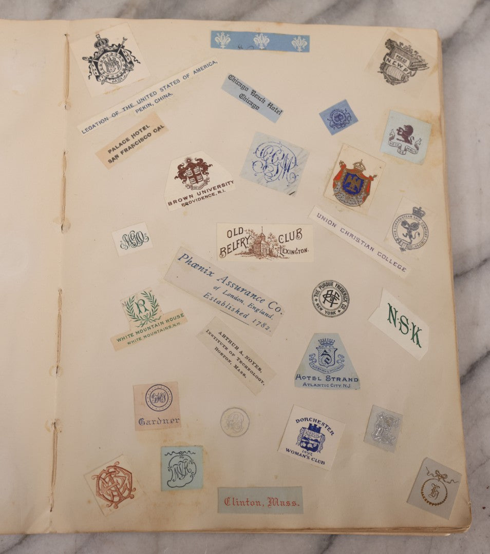 Lot 294 - Antique Scrapbook With Clipped Logos, Seals, And Institutional Names From Colleges, Hotels, Clubs, Banks, Government Offices, And More, Arranged By Color Throughout 20+ Pages, Marbled Cover Boards