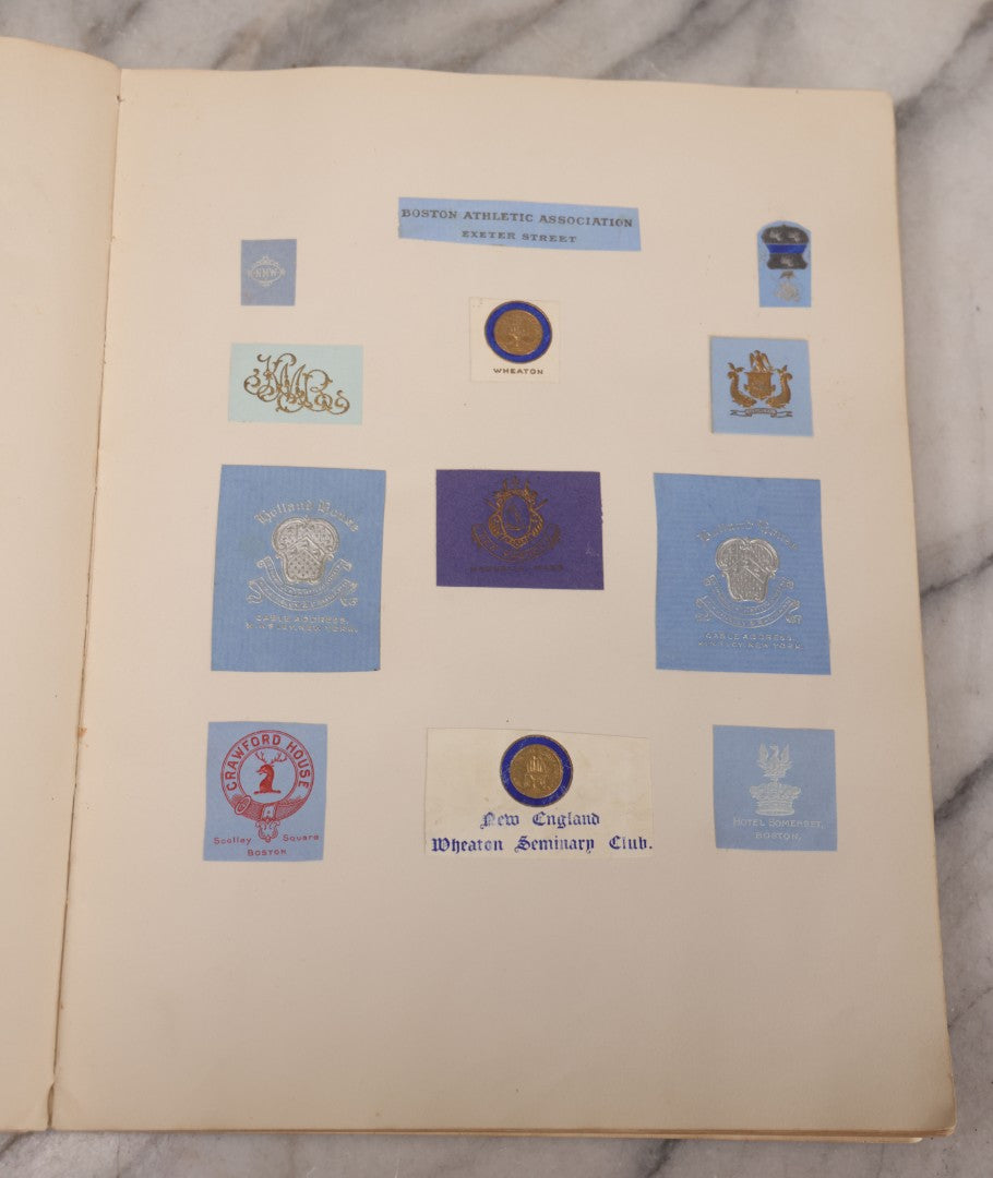 Lot 294 - Antique Scrapbook With Clipped Logos, Seals, And Institutional Names From Colleges, Hotels, Clubs, Banks, Government Offices, And More, Arranged By Color Throughout 20+ Pages, Marbled Cover Boards