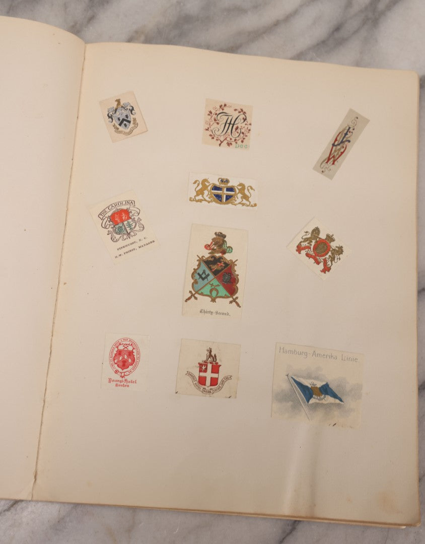 Lot 294 - Antique Scrapbook With Clipped Logos, Seals, And Institutional Names From Colleges, Hotels, Clubs, Banks, Government Offices, And More, Arranged By Color Throughout 20+ Pages, Marbled Cover Boards