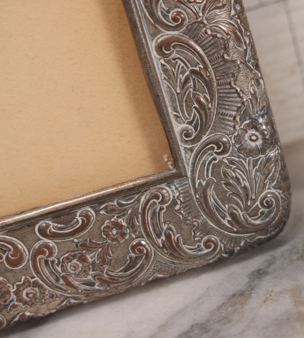 Lot 054 - Antique French Silvered Bronze Picture Frame With Repoussé Floral Scrollwork And Figural Scenes, With Glass, Circa Early 20th Century, 10-3/4" x 13-1/2"