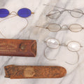 Lot 063 - Grouping Of Four Antique Wire Frame Spectacles Including Blue Lens Spectacles, With Two Partial Leather Cases, Edward E. Dammers, Worcester, Massachusetts