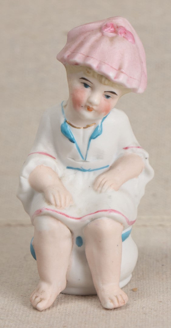 Lot 180 - Antique Bisque Figure of a Child With Pink Hat Seated on a Chamber Pot, Likely German, Note Severe Crack Across Midsection