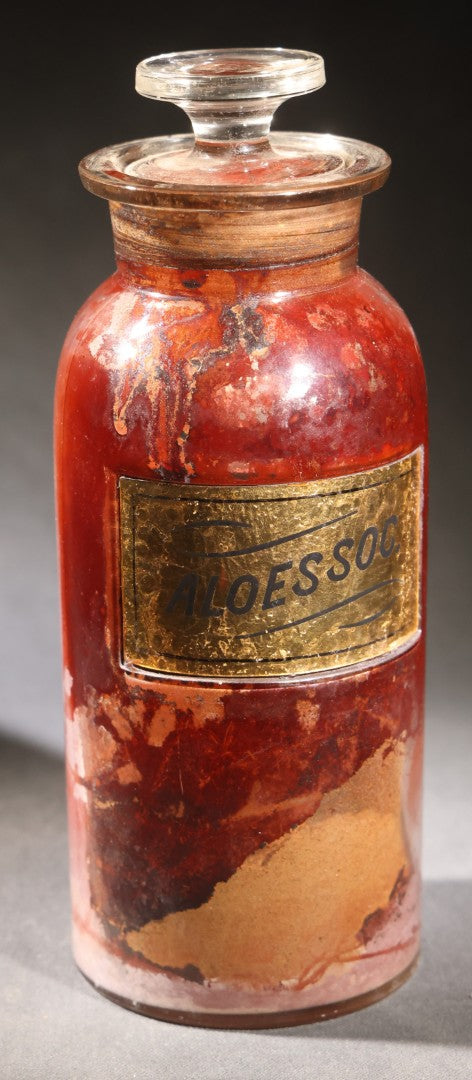 Lot 014 - Antique Apothecary Glass Jar, "Aloes Soc." (Socotrine Aloes), Reverse-Painted Gold Glass Label, Glass Stopper, Manufactured By Whitall Tatum Company, U.S.A..