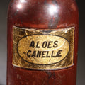 Lot 015 - Antique Apothecary Glass Jar, "Aloes Canellae" (Aloe And Canella Bark), Reverse-Painted Gold Glass Label With Oval Cartouche, Glass Stopper, Manufactured By Whitall Tatum Company, U.S.A.., 9-1/2" H