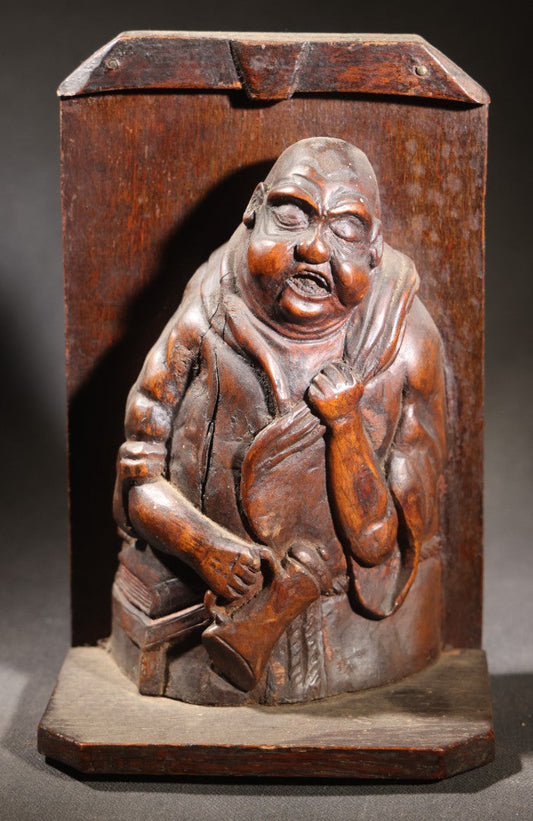 Lot 037 - Antique Folk Art Hand-Carved Wooden Figural Sculpture Of A Laughing Man With A Stein, Leaning On Books