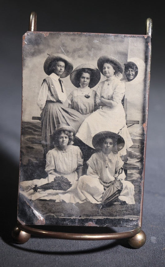Lot 120 - Antique Tintype Photograph Of Five Young Women In Wide-Brimmed Hats With Parasols, Man Peeking Through Hole In Studio Backdrop, Seaside Scene