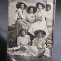 Lot 120 - Antique Tintype Photograph Of Five Young Women In Wide-Brimmed Hats With Parasols, Man Peeking Through Hole In Studio Backdrop, Seaside Scene