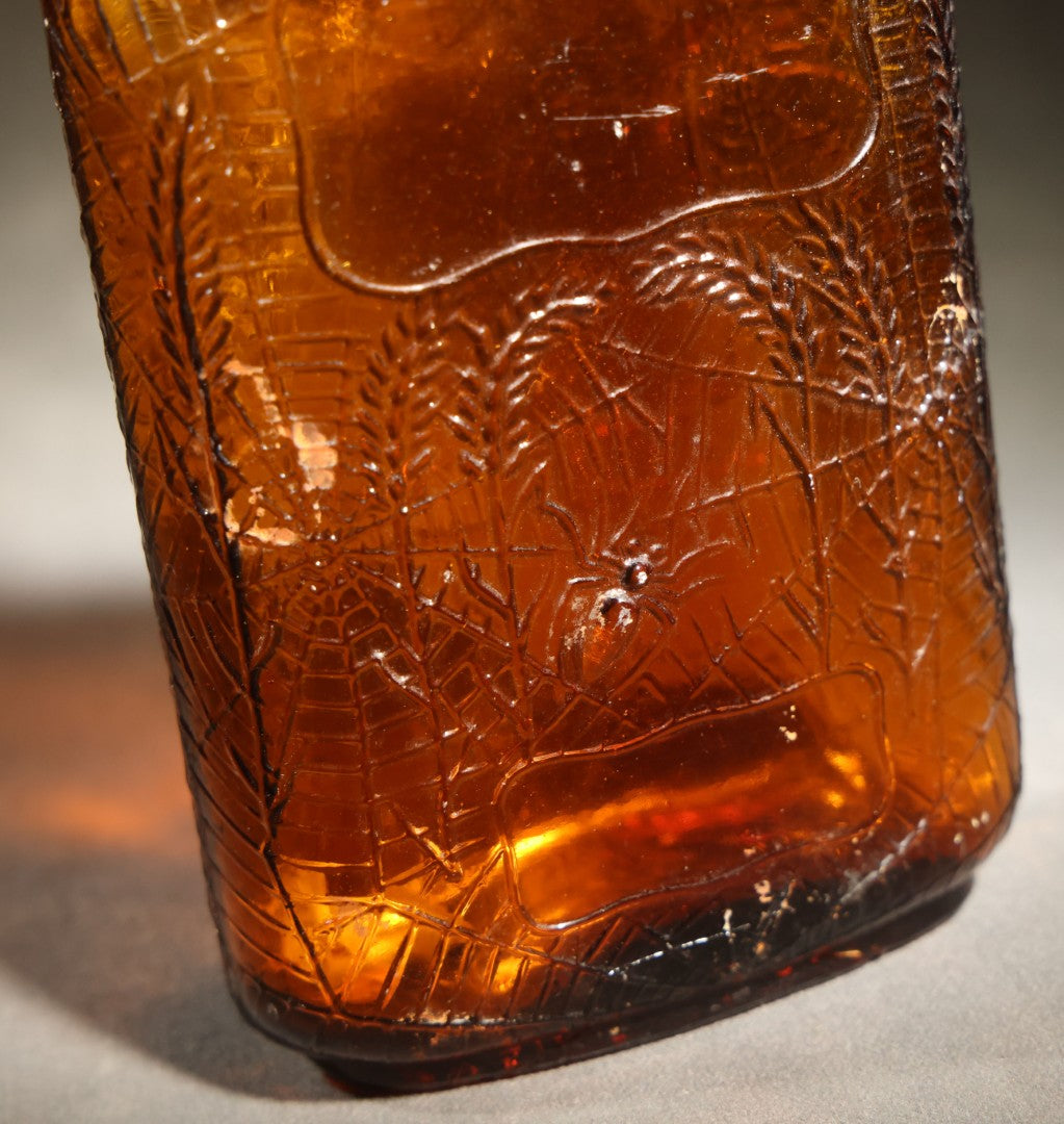 Vintage Embossed Amber Glass Whiskey Bottle with Spider Web, Spider, and Wheat Motifs, Marked "Non Refillable" and "Pat. Pending"