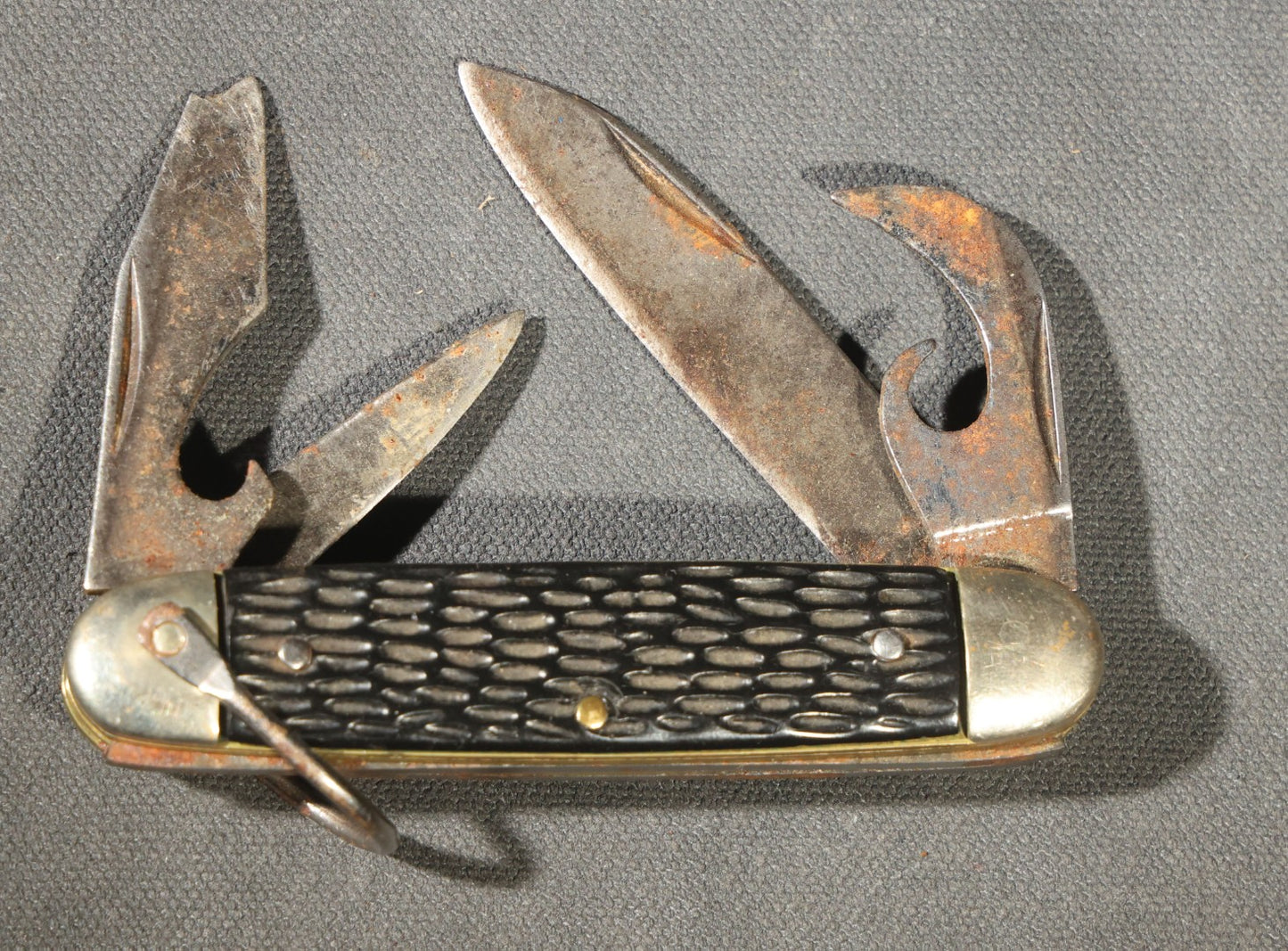 Grouping of Seven Vintage Folding Pocket Knives Including Multi-Tool Camp Knives, Stockman, and Trapper Styles with Bone, Jigged, and Composite Handles