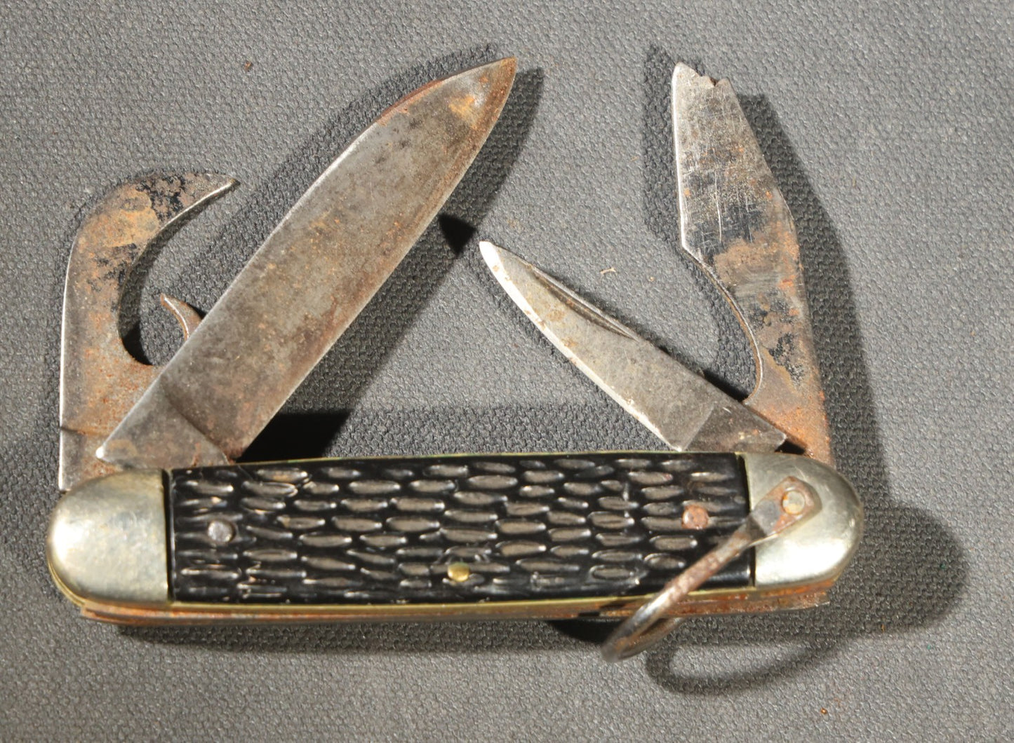 Grouping of Seven Vintage Folding Pocket Knives Including Multi-Tool Camp Knives, Stockman, and Trapper Styles with Bone, Jigged, and Composite Handles