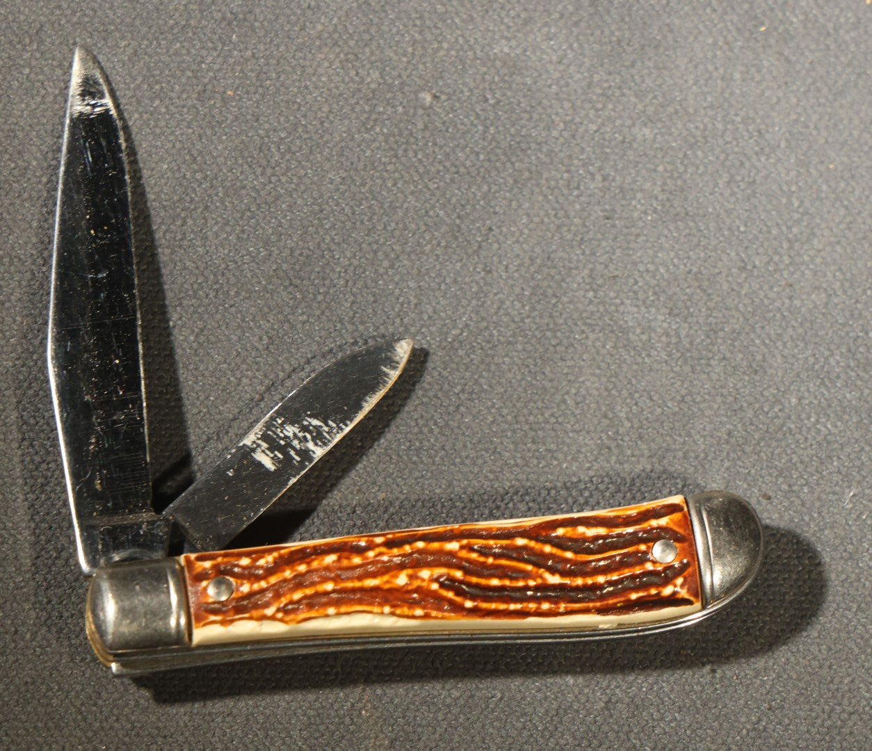 Grouping of Seven Vintage Folding Pocket Knives Including Multi-Tool Camp Knives, Stockman, and Trapper Styles with Bone, Jigged, and Composite Handles