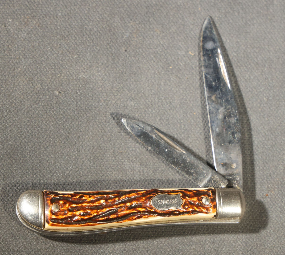 Grouping of Seven Vintage Folding Pocket Knives Including Multi-Tool Camp Knives, Stockman, and Trapper Styles with Bone, Jigged, and Composite Handles