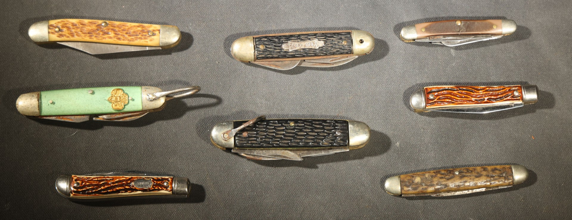 Grouping of Seven Vintage Folding Pocket Knives Including Multi-Tool Camp Knives, Stockman, and Trapper Styles with Bone, Jigged, and Composite Handles