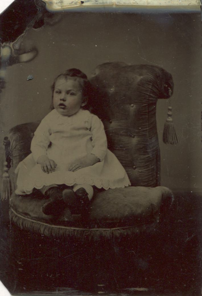 Tintype Photograph of a Young Baby Girl In a White Dress Seated in a Chair